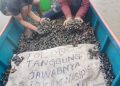Nelayan Muara Badak menunjukkan tumpukan kerang mati akibat pencemaran, dengan spanduk bertuliskan "Tolong tanggung jawabnya, pikirkan nasib kami