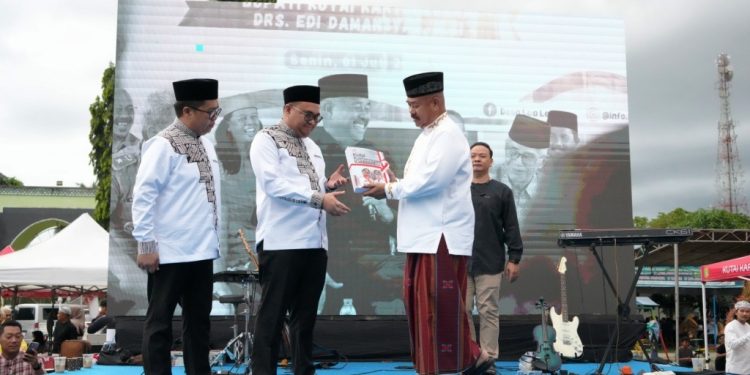 Edi Damansyah menyerahkan memori jabatan kepada Bupati Kukar Aulia Rahman Basri, didampingi Rendi Solihin, dalam acara serah terima jabatan di Masjid Agung Tenggarong, 30 Juni 2025.