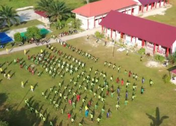 Foto udara SMPN 7 Muara Badak di tengah perkebunan kelapa sawit dengan siswa beraktivitas di halaman sekolah