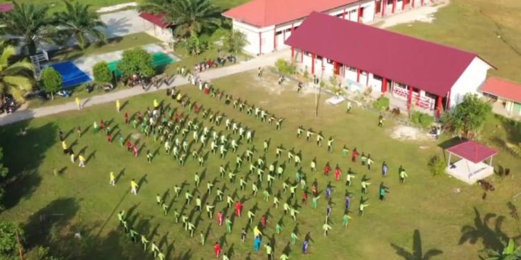 Foto udara SMPN 7 Muara Badak di tengah perkebunan kelapa sawit dengan siswa beraktivitas di halaman sekolah